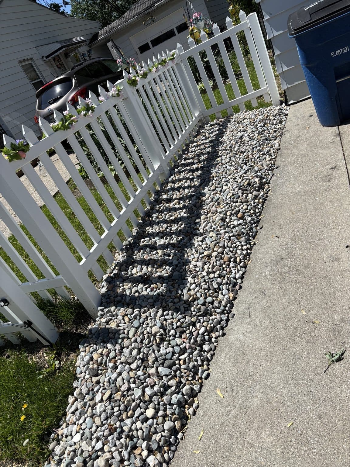 Decorative rock installed beside a walkway and white fence by Clean Edge